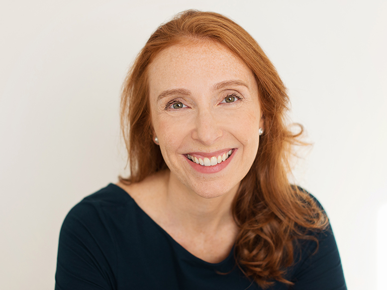 Dr Kathryn Levy in a black top with her hair down smiling at the camera.